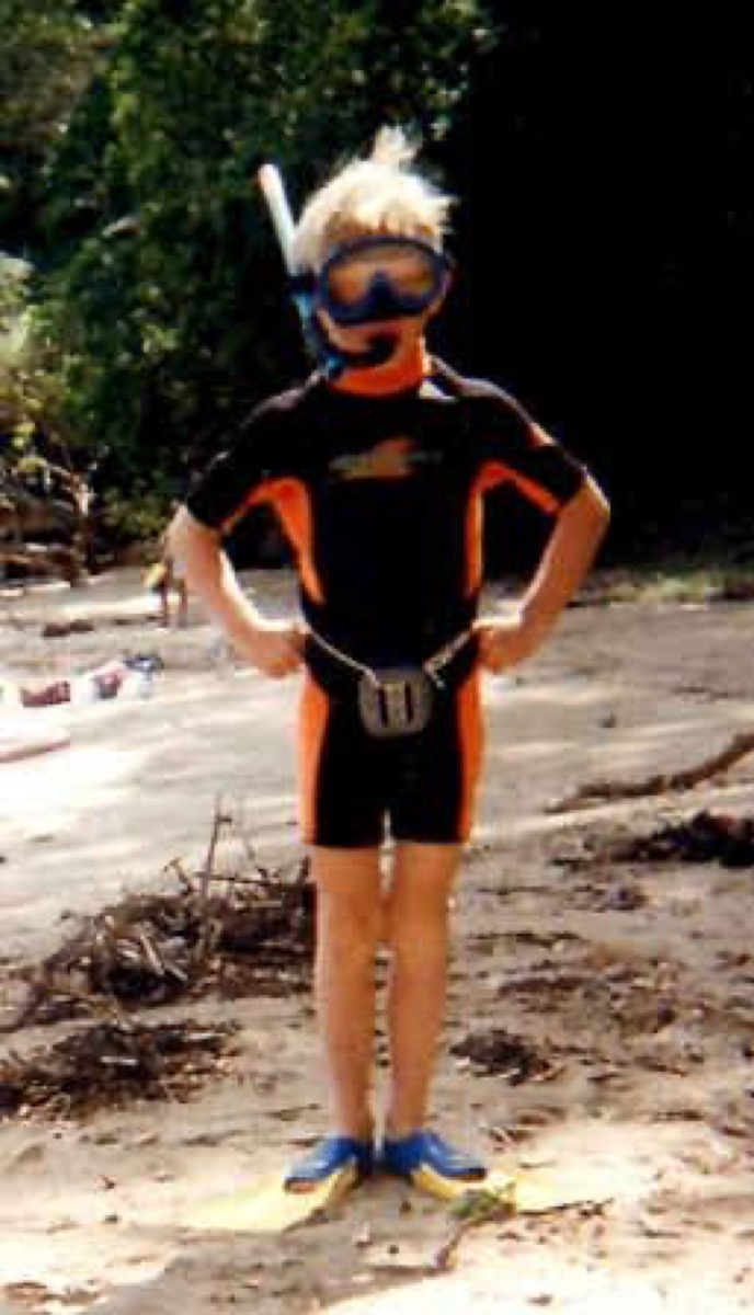 Alex as a child in wetsuit and snorkel gear on the beach