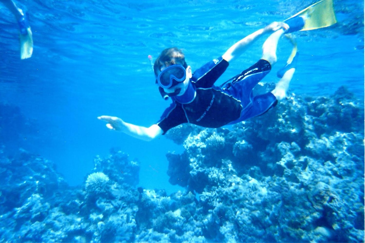 Alex as a child snorkelling over a reef